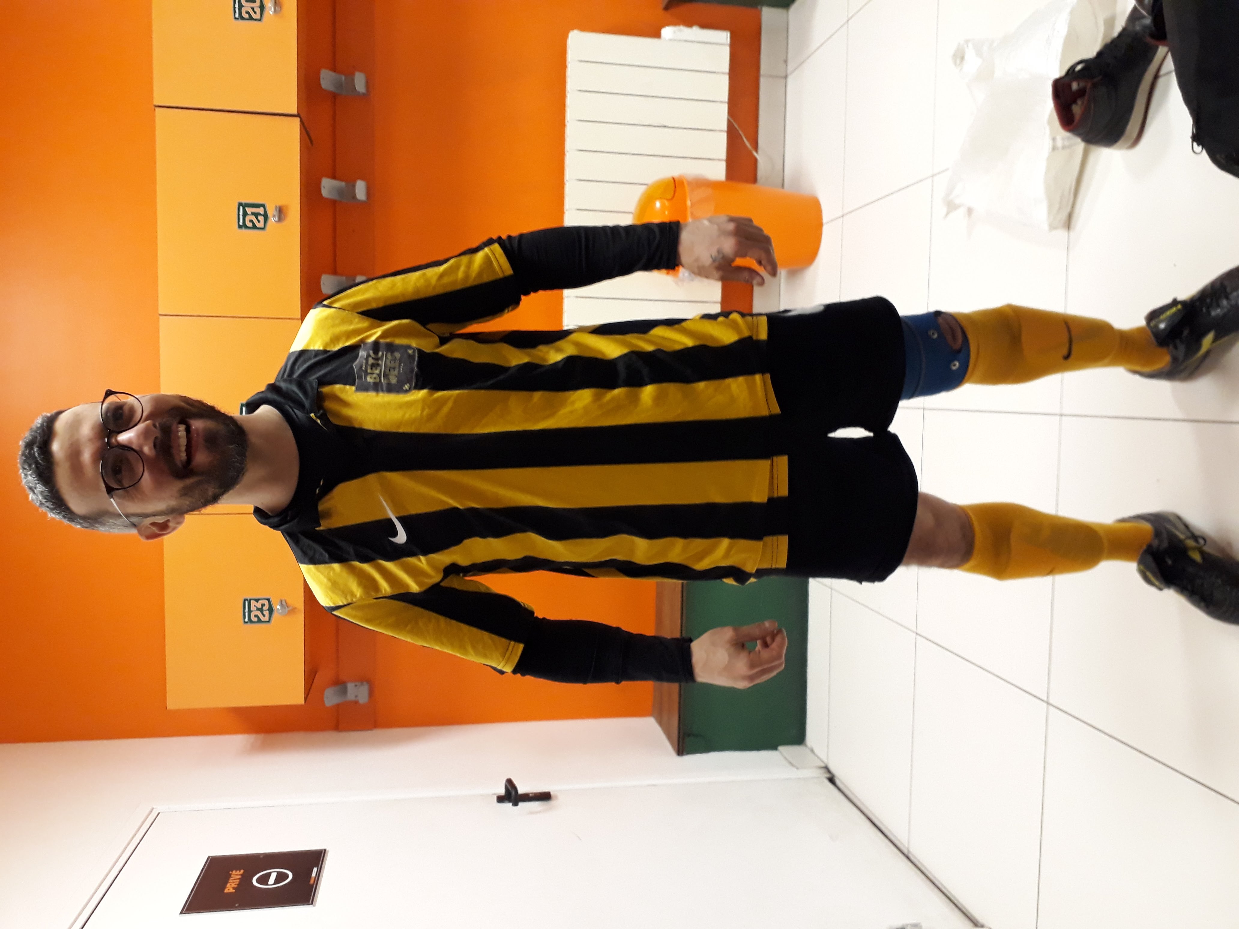 Je apparais dans un vestiaire lumineux, debout au centre de la pièce, dans la tenue de foot de BETC.