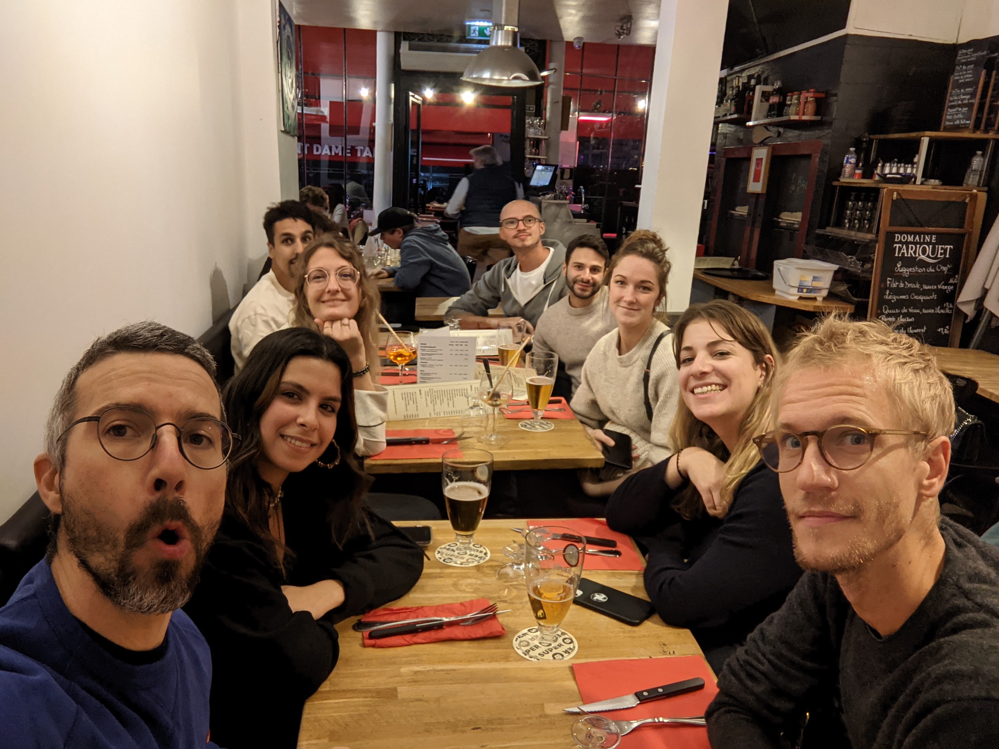 Groupe d’amis souriant autour d’une table de restaurant avec verres et bouteilles.