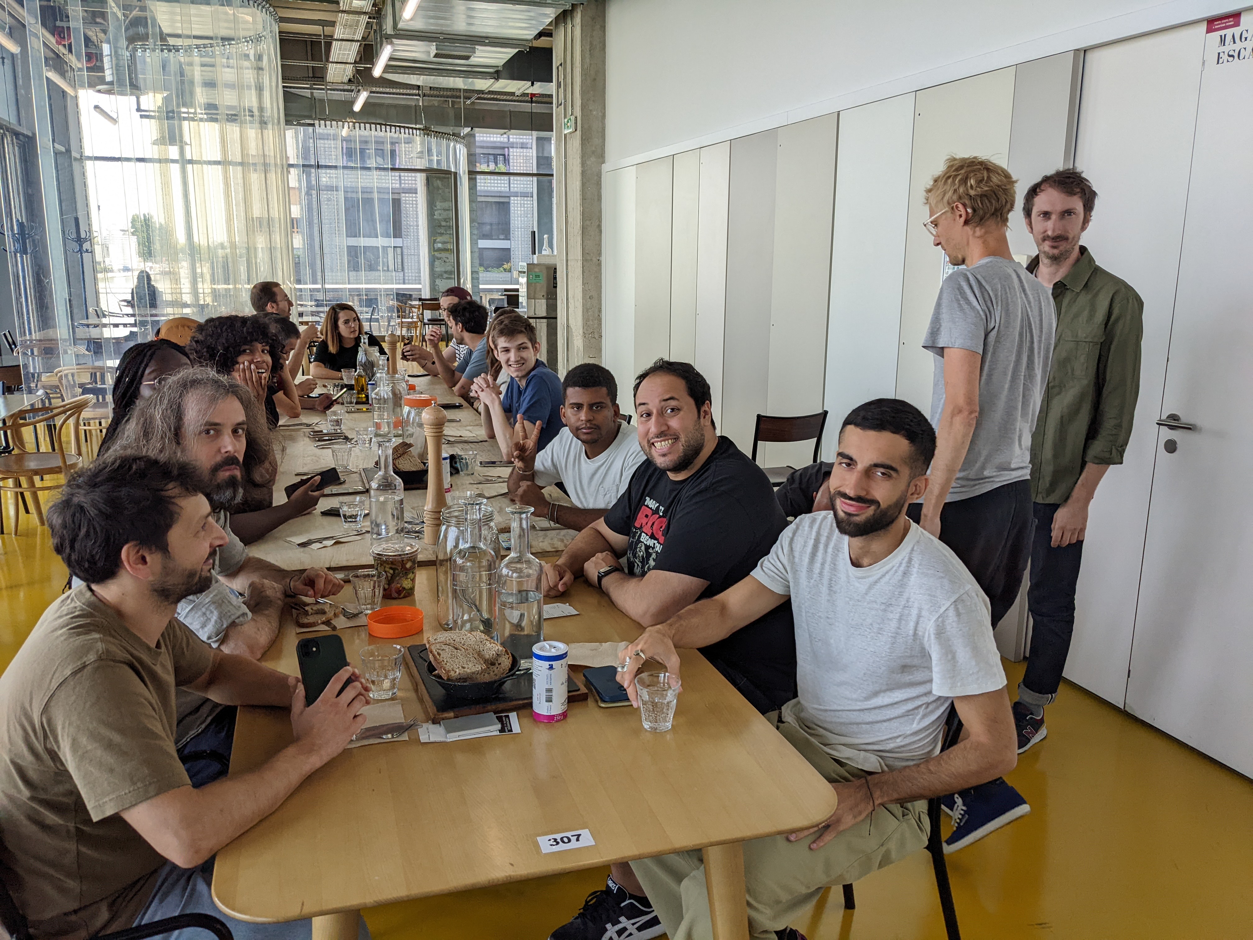 Grande tablée conviviale dans un espace lumineux, personnes souriant face à l’appareil photo.