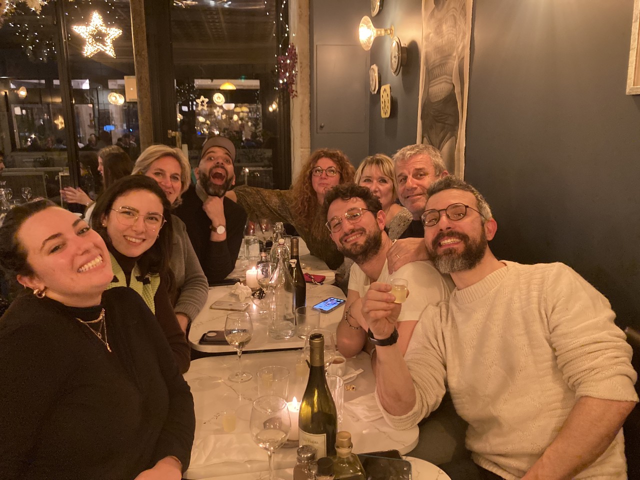 Groupe d’amis réunis autour d’une table au restaurant le soir, ambiance chaleureuse et éclairage tamisé.